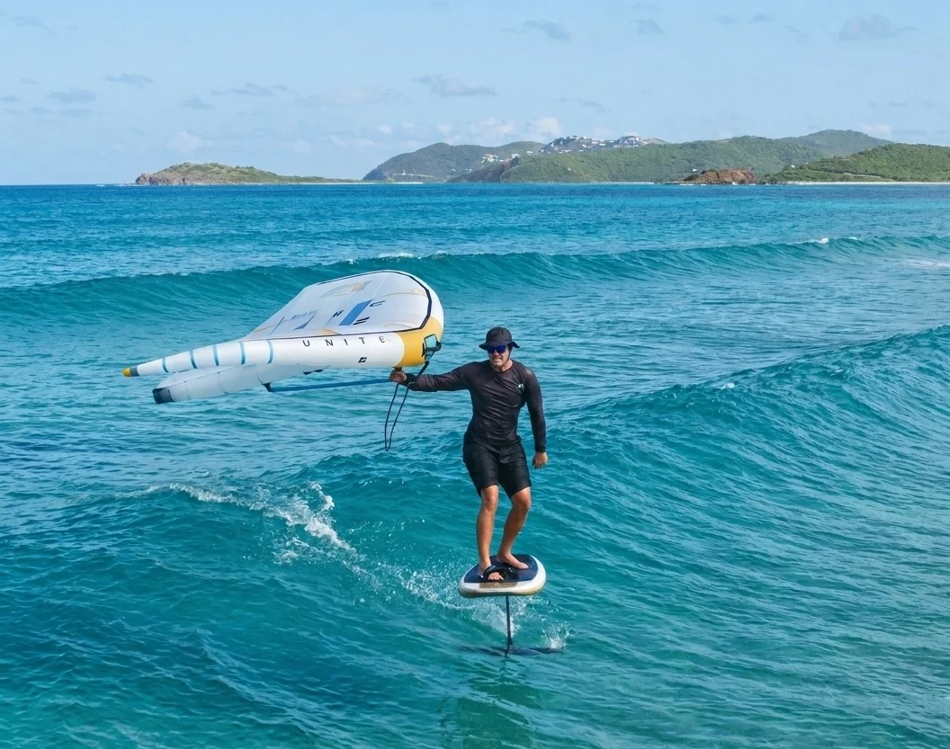 Rider en wingfoil au-dessus d'une eau turquoise, îles des Antilles en arrière-plan